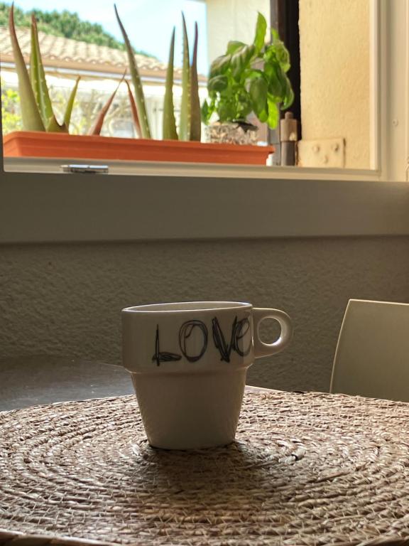 Una taza de café con la palabra amor escrita sobre una mesa. en Plain pied - Appartement dans résidence sous les pins, en Cap d'Agde