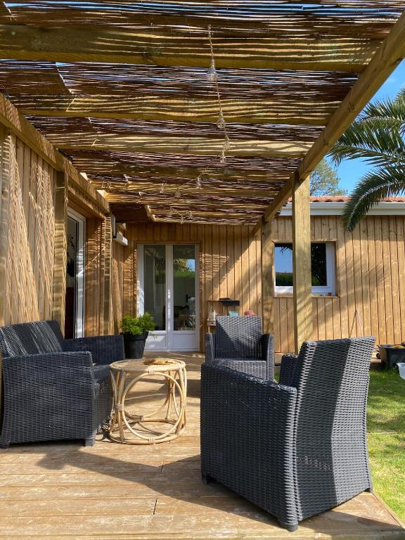 un patio avec des chaises en osier et une table dans l'établissement Maison familiale, 4 chambres, à Tarnos