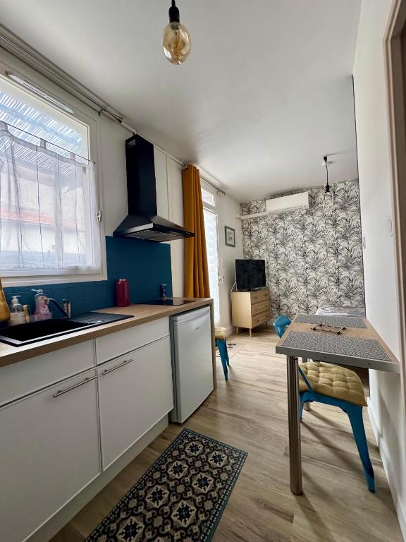 une cuisine avec un évier et une table à l'intérieur dans l'établissement L'escapade Angoumoisine, studio idéalement situé, à Angoulême