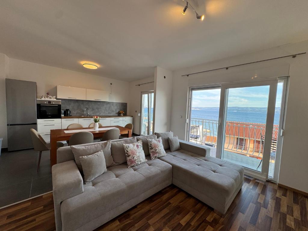 a living room with a large couch and a kitchen at Apartment Marino 2 in Duće