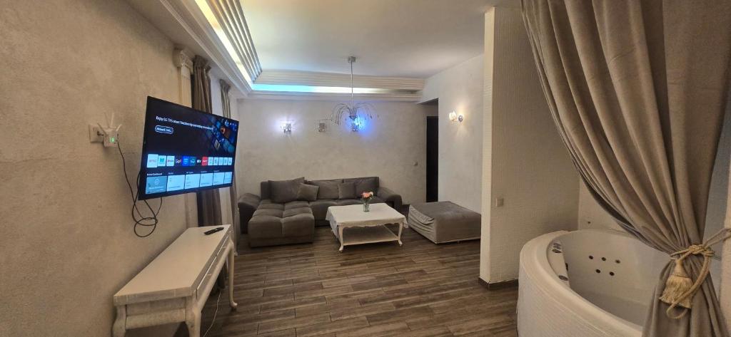 ヴィリニュスにあるApartamentai su jacuzziのソファとバスルームのテレビがあるリビングルーム