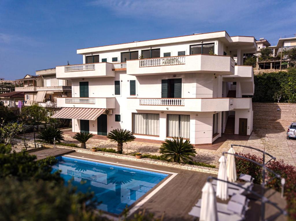 a large white building with a swimming pool in front of it at Villa La Quiete - Adults only in Ksamil