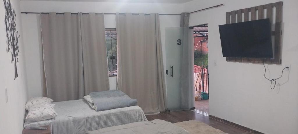 een woonkamer met een tv en een stoel in een kamer bij Hospedaria Dona Clara in Tiradentes