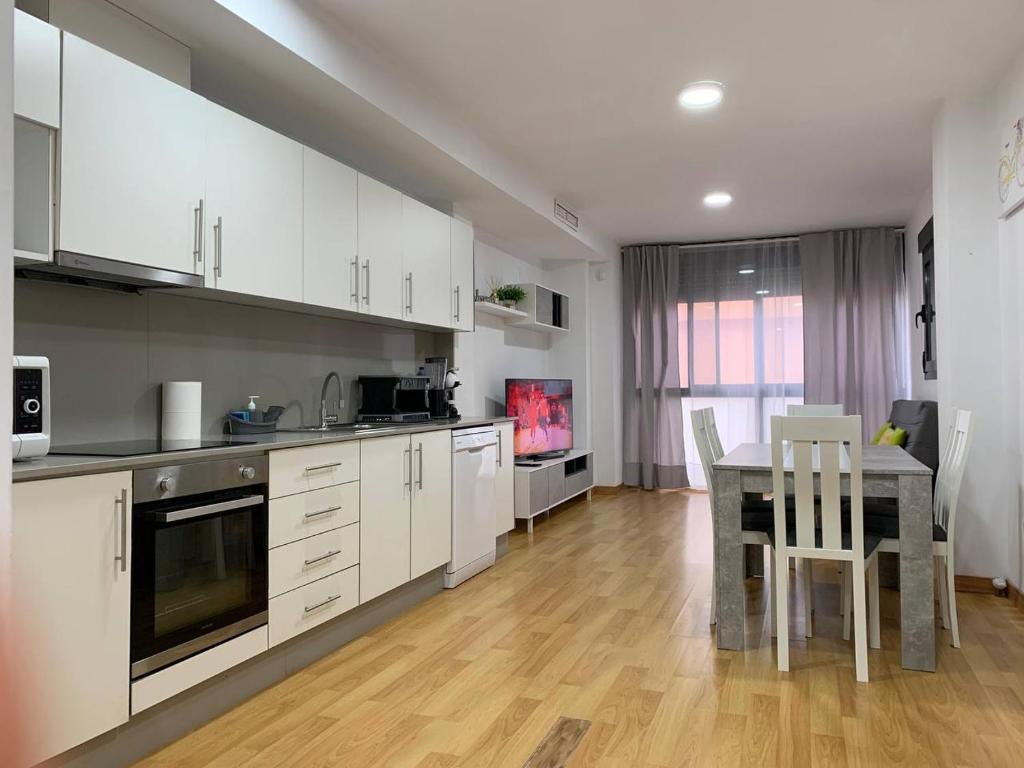 eine Küche mit weißen Schränken und einem Tisch mit Stühlen in der Unterkunft Sunrise Beach Apartment Playa Puerto de Sagunto in Puerto de Sagunto