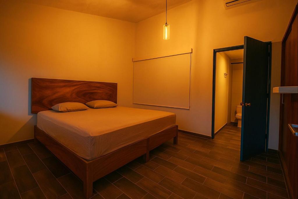 a bedroom with a bed with a board on the wall at Casa Tobala in Acapulco
