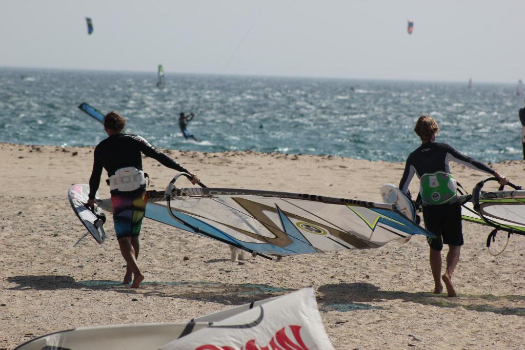 a group of people walking on the beach with their surfboards at Hostal Brisa Marina in Port d'Alcudia