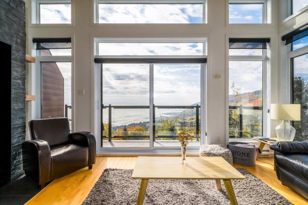 ein Wohnzimmer mit Tisch und großem Fenster in der Unterkunft Le Saint-Laurent in Petite-Rivière-Saint-François
