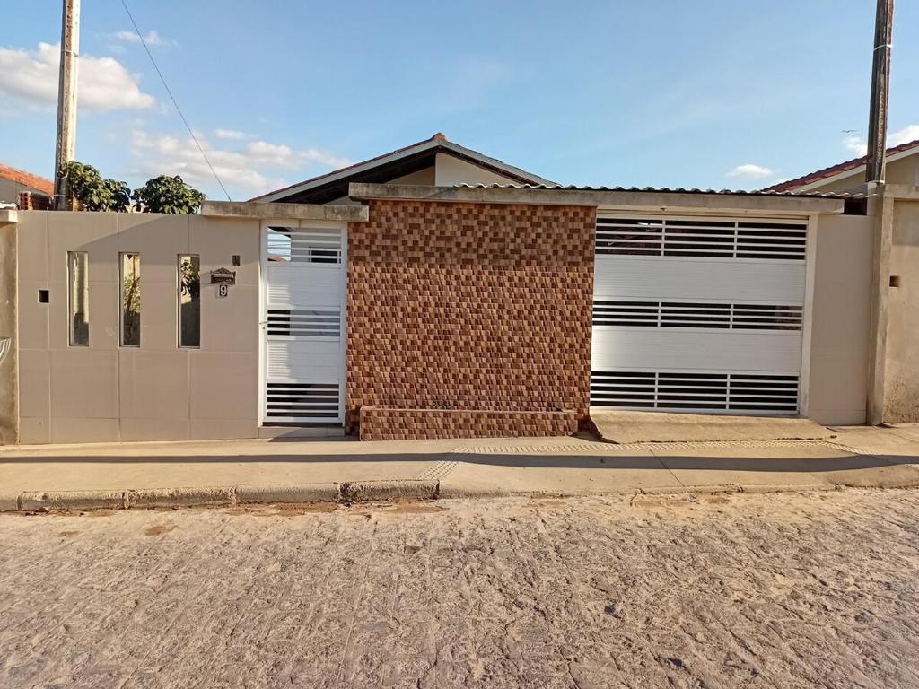 a house with white garage doors on a street at Encantos do Natal em Garanhuns in Garanhuns