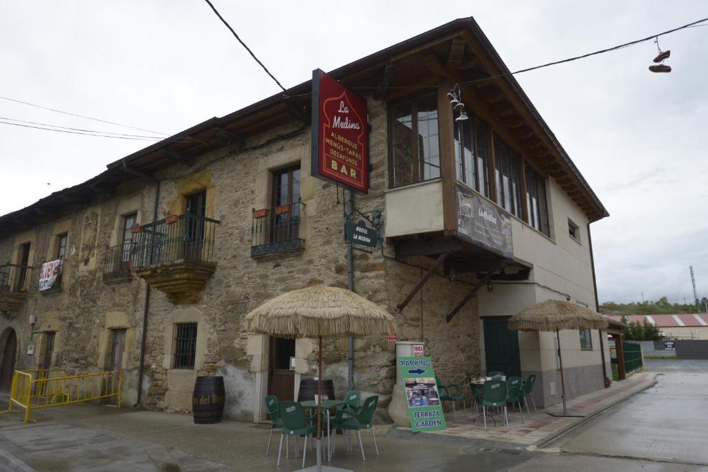 a building with tables and chairs in front of it at Albergue la Medina de Camponaraya in Camponaraya