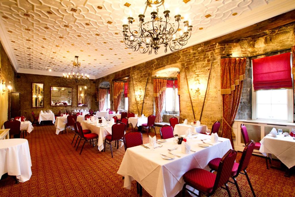 un restaurante con mesas y sillas blancas y una lámpara de araña en Angel and Royal Hotel, en Grantham