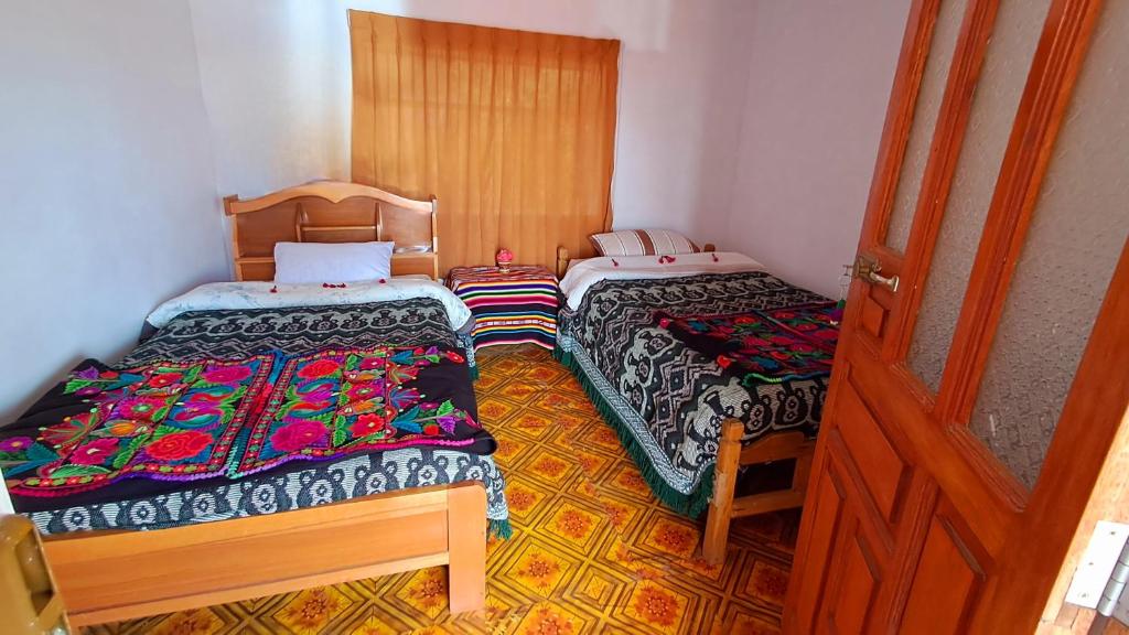 a room with two beds and a wooden door at Munay Wasi in Puno