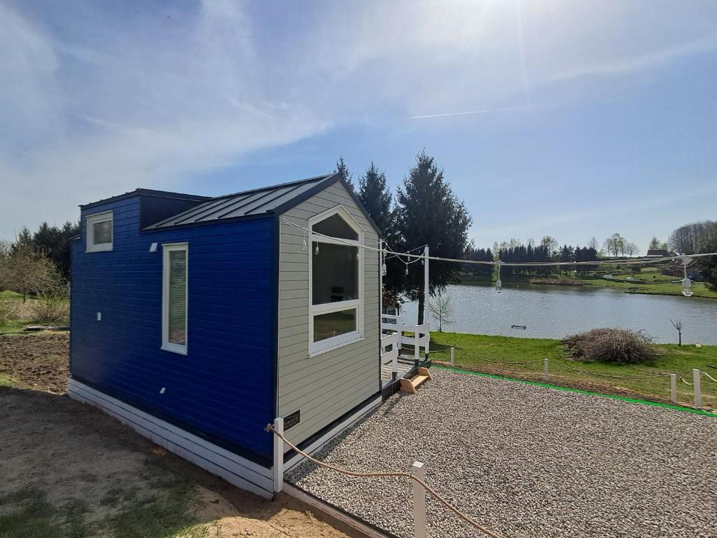 a blue and gray tiny house next to a lake at Mazurski Domek Papy Smerfa plaża pomost jezioro prywatny staw gospodarstwo pasieka in Leśniewo