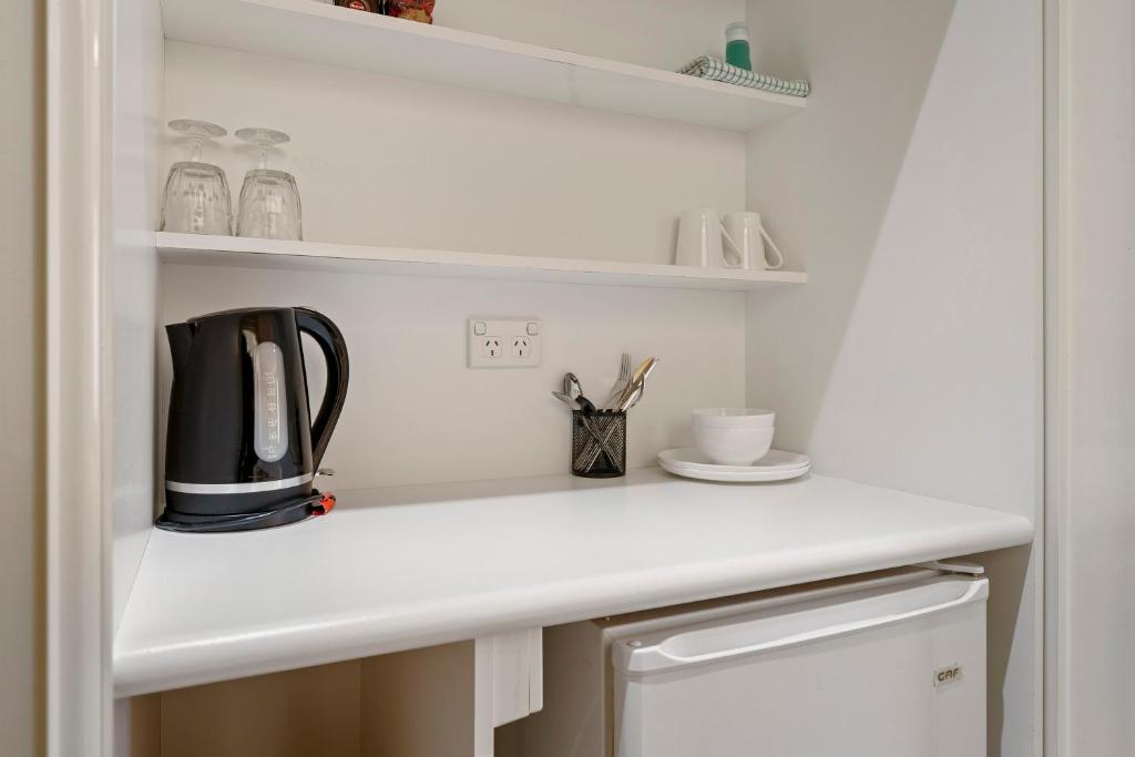 a kitchen counter with a coffee maker on a shelf at Comfort Inn Devonport in Devonport