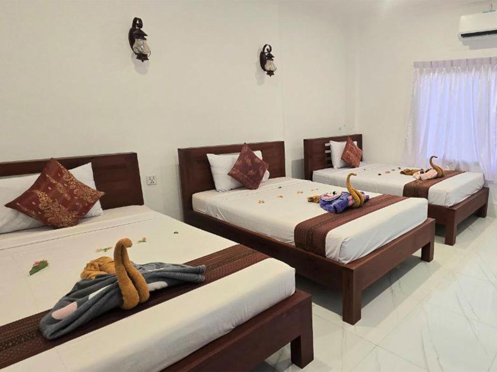 a room with three beds with towels on them at Blossoming Romduol Boutique in Siem Reap