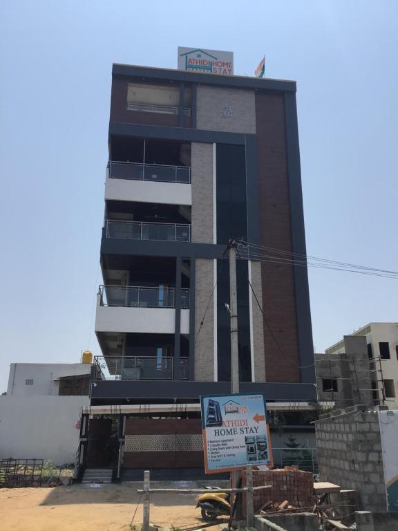 ティルパティにあるAthidi Luxury Home Stay - AC 2BHK Fully Furnished Flat with TV, WI-FI, 24Hrs Hot water, Parking, Elevator, Power Backupの前に看板がある高い建物