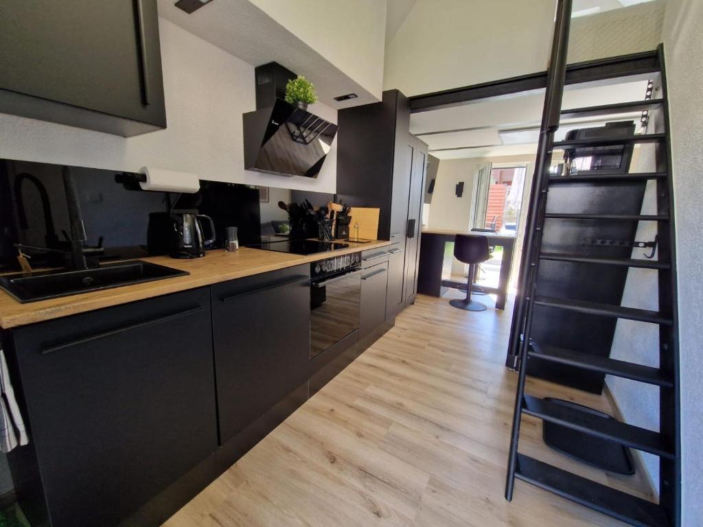 a kitchen with black cabinets and a wooden floor at Tiny House am See Dillich - Schwimmteich - Klimaanlage - Hunde willkommen - Eigener Garten in Borken