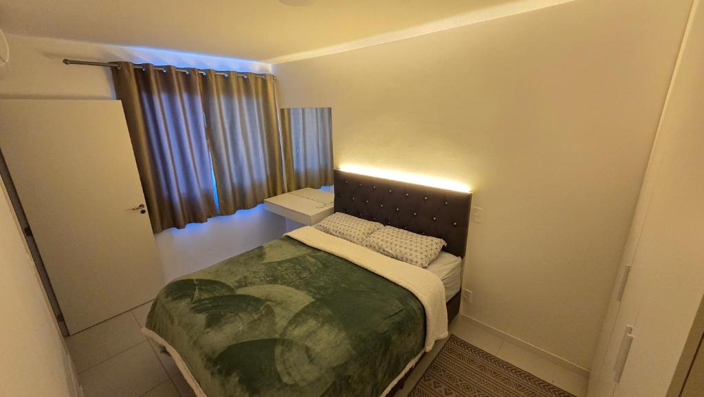 a small bedroom with a bed and a window at Apto completo, Piscina, Cinema, Home Clube e Jardim in Piçarras