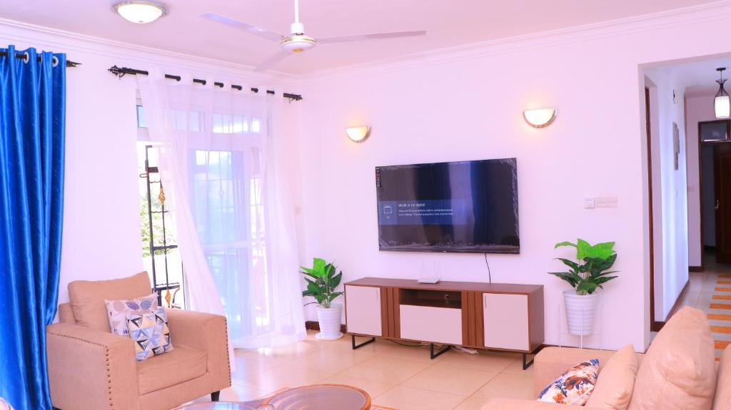 Una sala de estar con un televisor de pantalla plana en una pared blanca. en TANISHIA APARTMENTS, en Mombasa