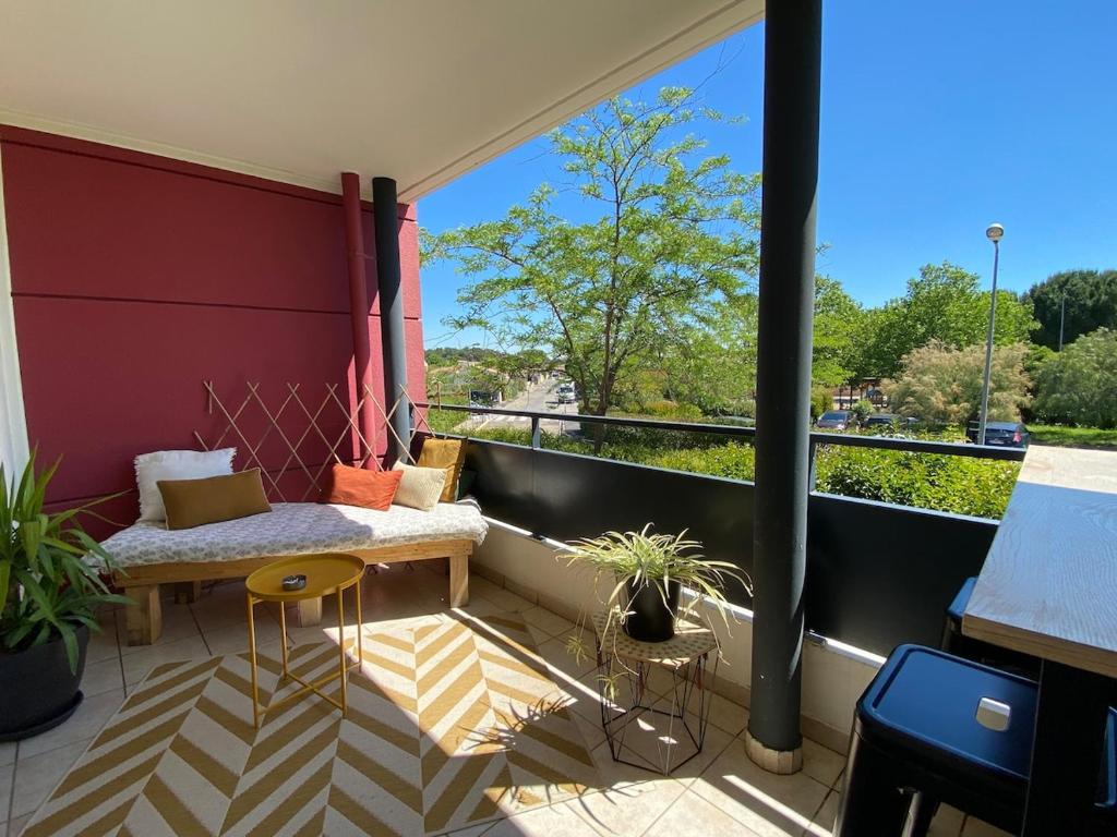 - un balcon avec un banc et une table dans un bâtiment dans l'établissement Joli appartement cosy , terrasse, PK privé, à Lunel
