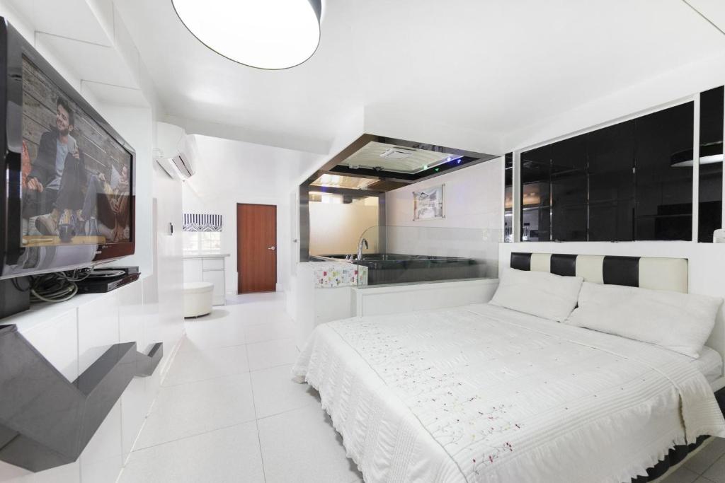 a white bedroom with a large bed and a kitchen at Gapyeong Belita pension in Gapyeong