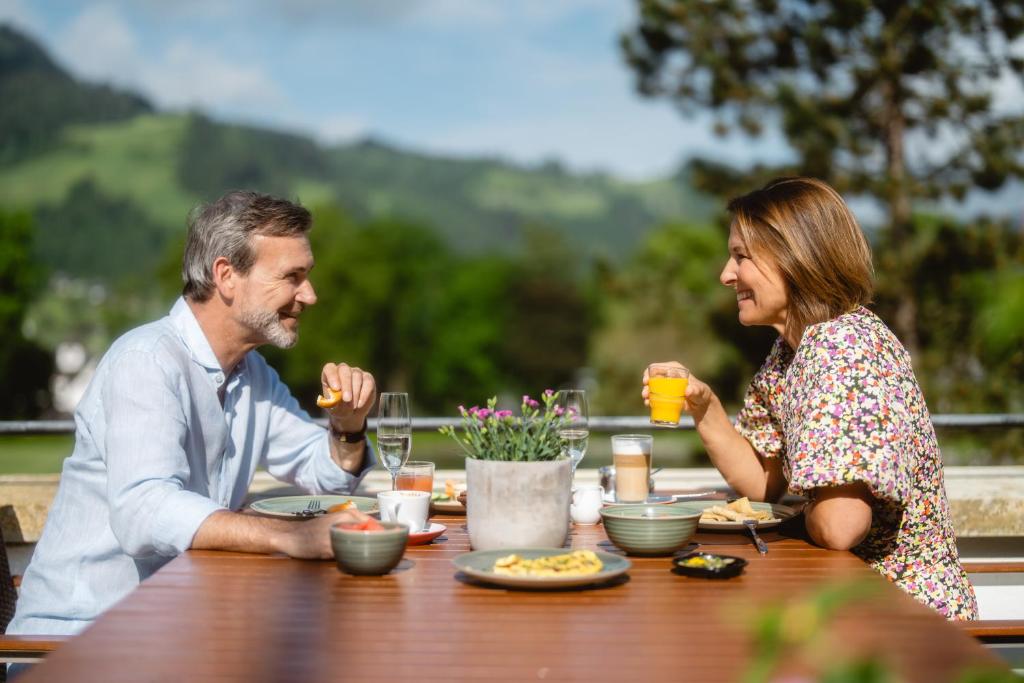 a man and woman sitting at a table eating food at Schlosshotel Kitzbühel A-ROSA Collection in Kitzbühel