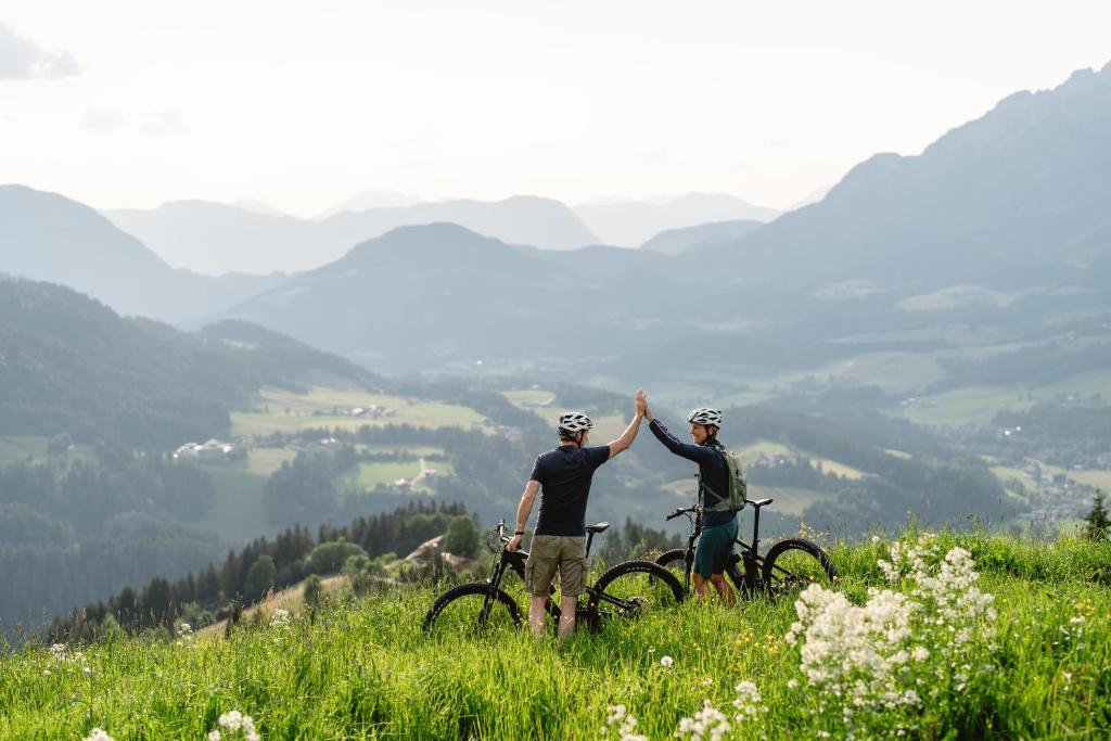 two men standing on top of a hill with their bikes at Schlosshotel Kitzbühel A-ROSA Collection in Kitzbühel