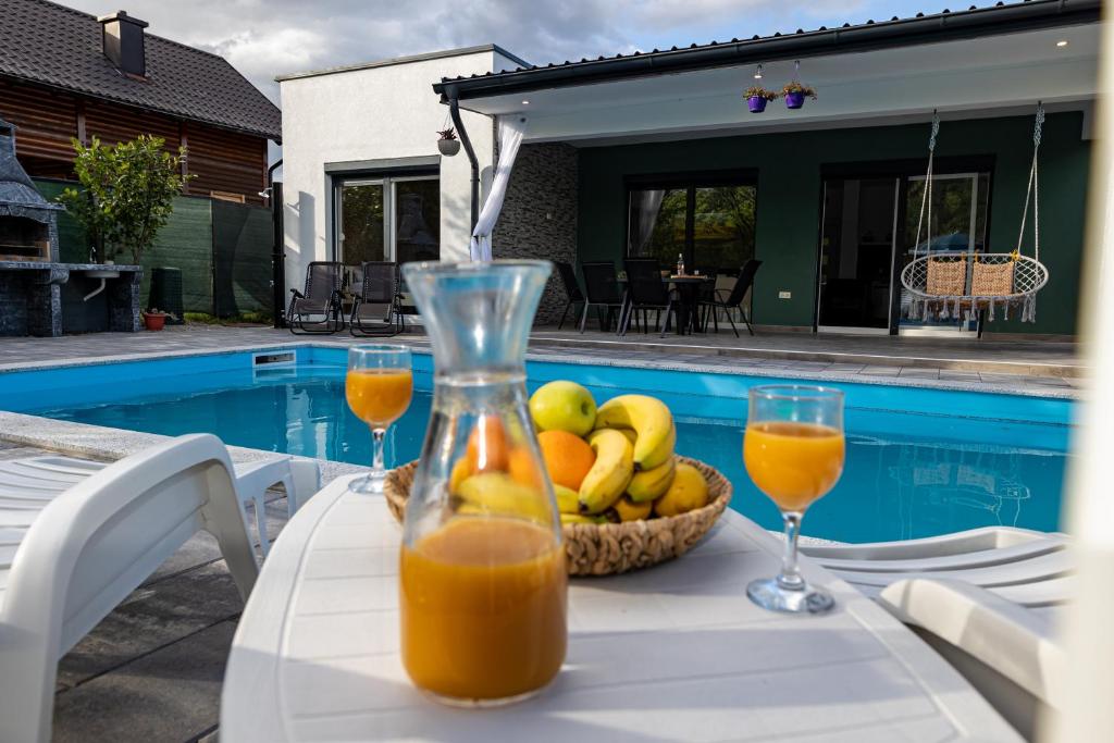 a table with a bowl of fruit and two glasses of orange juice at simply-una in Bihać
