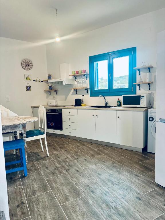 a kitchen with white cabinets and a blue window at Boutique Village in Leipsoi