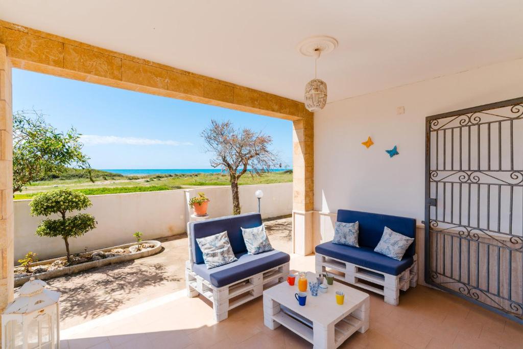 a living room with two blue chairs and a table at Fronte Mare Villa Raffaele in Punta Prosciutto