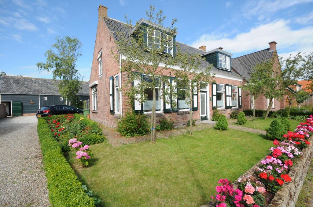 una casa de ladrillo con flores en el patio en Gastenverblijf Neeltje, en Oostkapelle