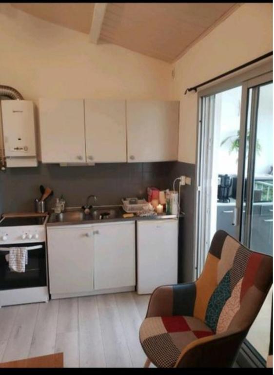 une cuisine avec des armoires blanches et un four à plaques de cuisson dans l'établissement Bel appartement proche plage richelieu, au Cap d'Agde