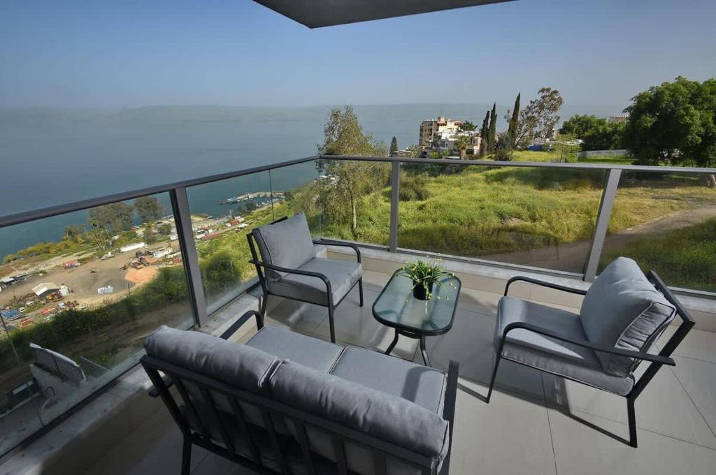 Ariston First Line Lake View في طبرية: شرفة مع كراسي وطاولة وإطلالة على المحيط