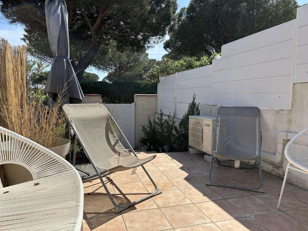 - une terrasse avec des chaises, un barbecue et un parasol dans l'établissement SP310-013 Maison studio mezzanine 4 couchages SAINT PIERRE LA MER, à Saint Pierre La Mer