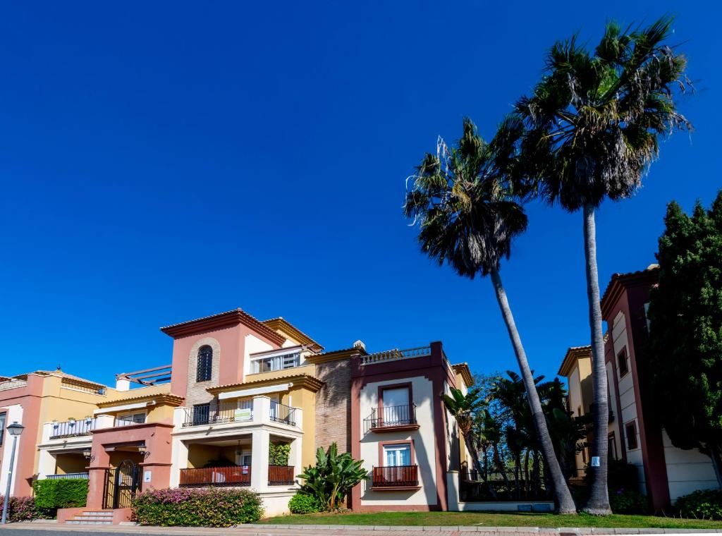 een gebouw met twee palmbomen ervoor bij apartamento campo de golf Isla Canela in Isla Canela