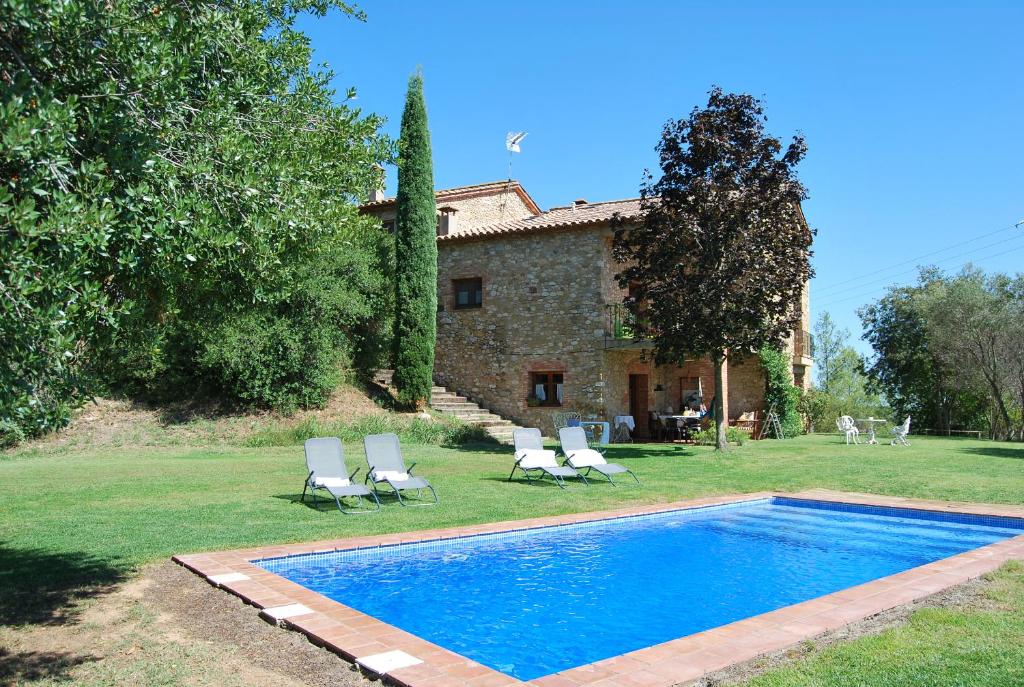 a swimming pool in front of a house with chairs at Masia Can Sisó in Crespiá