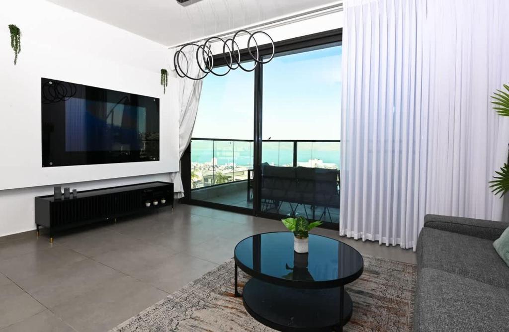 a living room with a couch and a table and a tv at Michelangelo Kinneret Family Apartment in Tiberias
