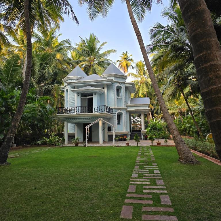 a house with palm trees in front of a yard at Sea Breeze, Guhagar in Guhagar