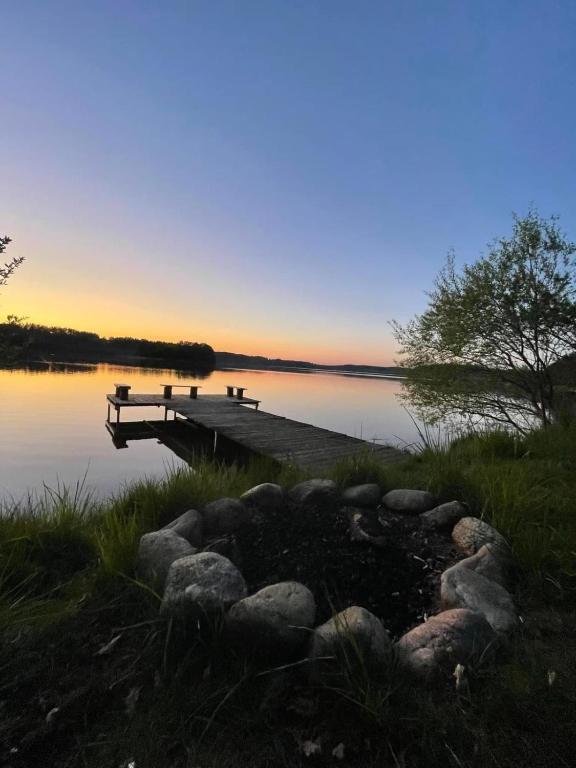 a dock on a lake with a sunset in the background at Mały Karmelowy Domek in Stężyca