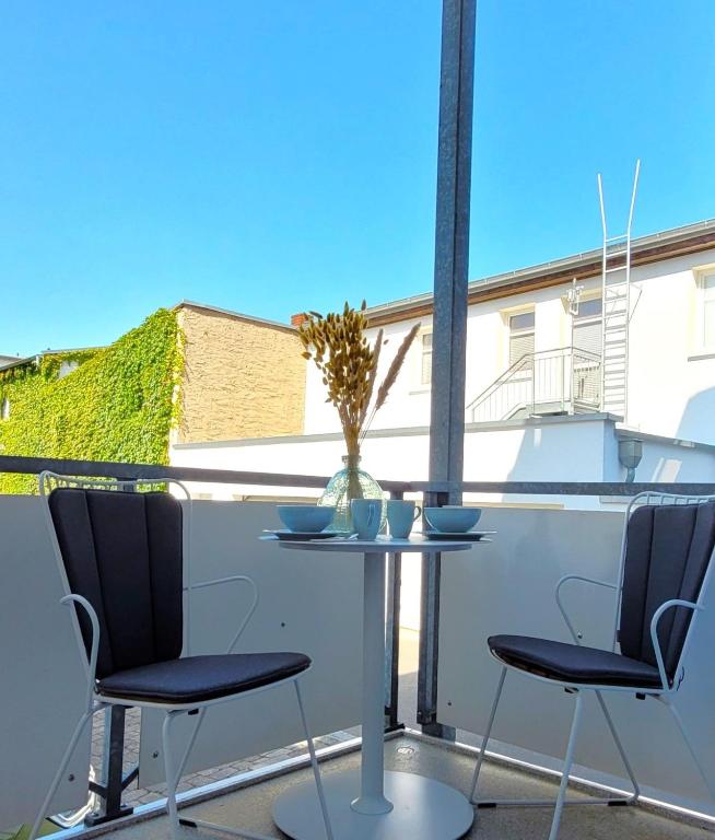 a table with two chairs and a vase on a balcony at Warnemünde Fischer`s Hus 10139 in Rostock