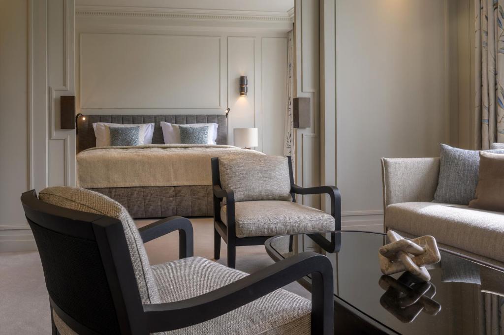 a bedroom with a bed and two chairs and a table at Hotel Bayerischer Hof in Munich