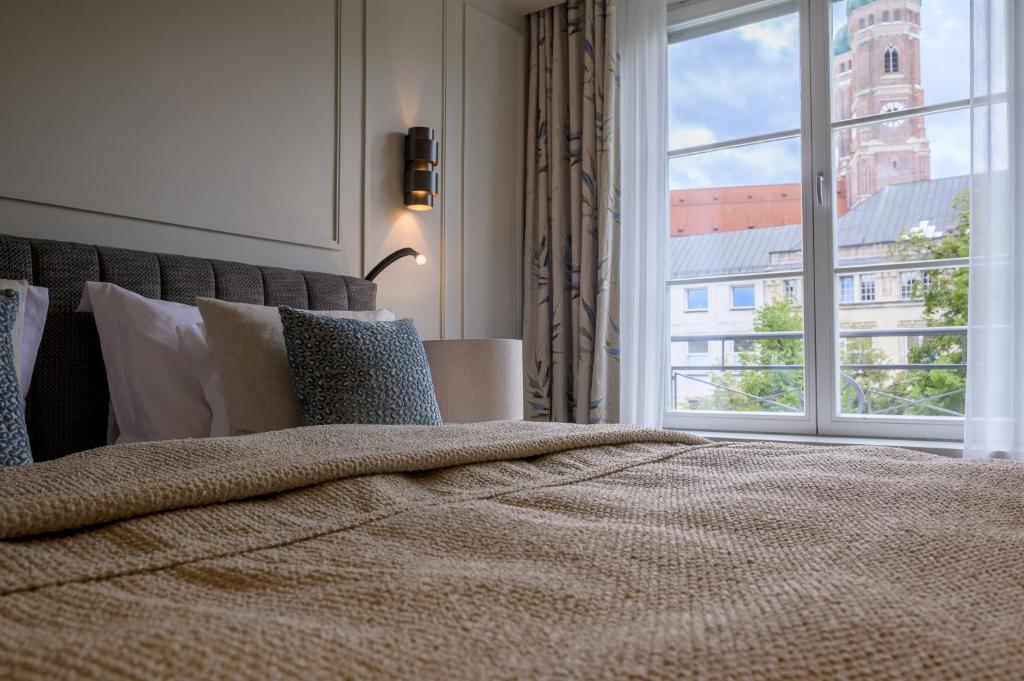 a bedroom with a large bed with a large window at Hotel Bayerischer Hof in Munich