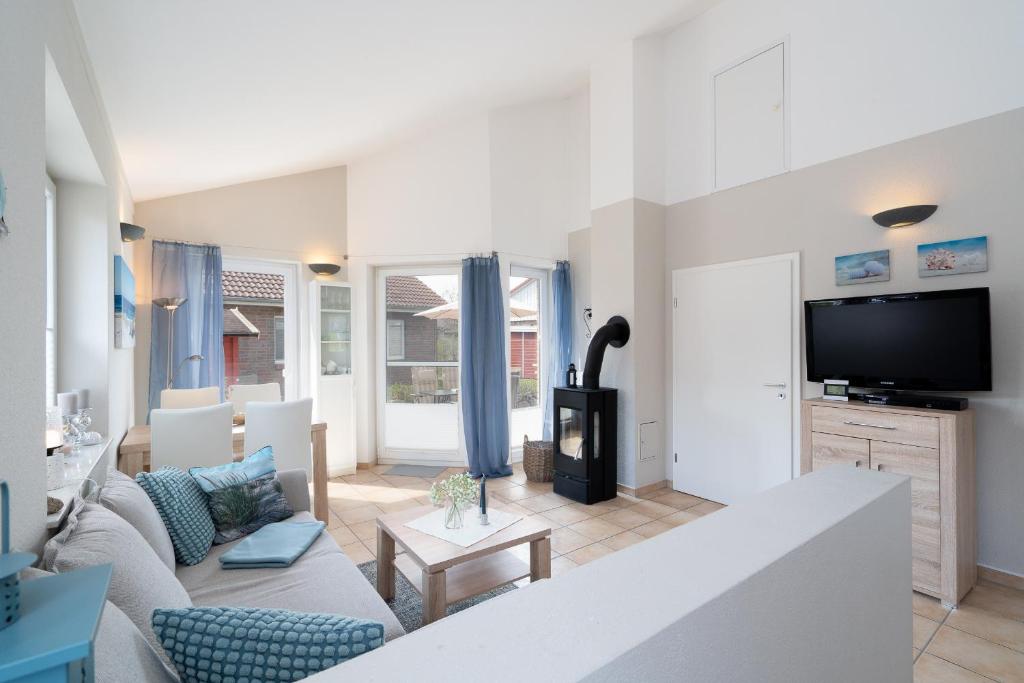 a living room with a couch and a tv at Feriendorf Südstrand Haus 18 in Pelzerhaken