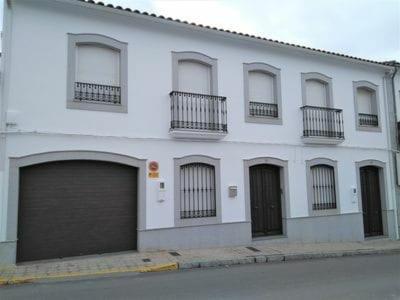 a white building with two garage doors and windows at Piso Calle Pelayo in Villanueva de Córdoba