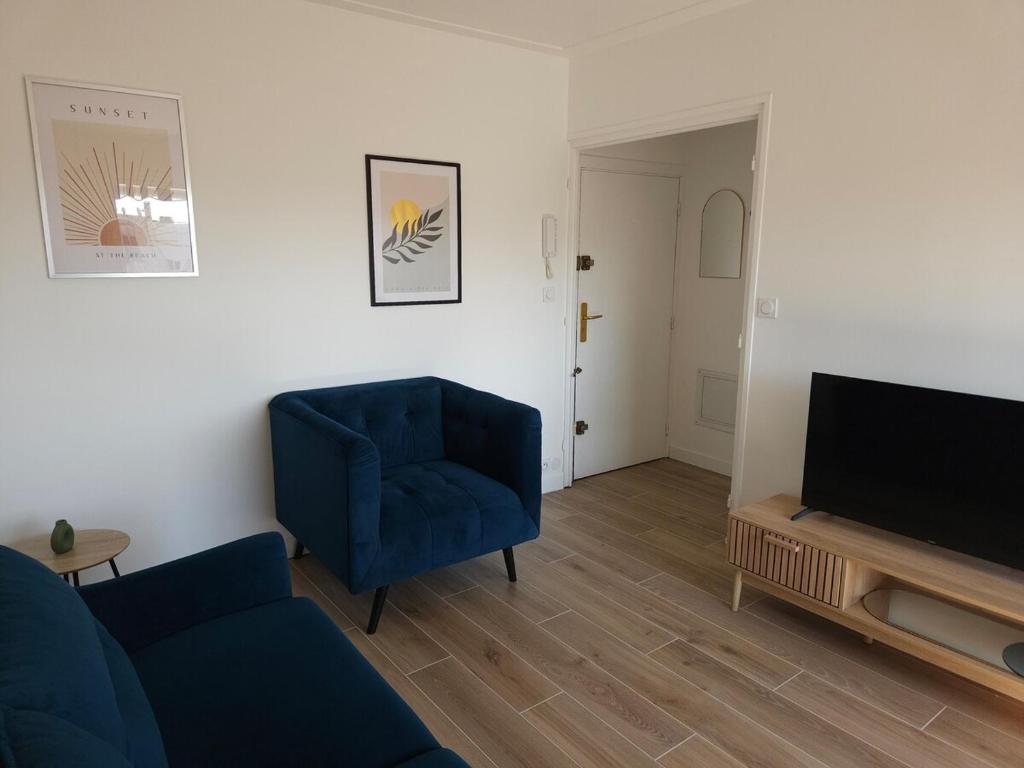 un salon avec une chaise bleue et une télévision dans l'établissement Beau studio, Le Lérins Centre Juan-les-Pins , 150m des plages, à Antibes