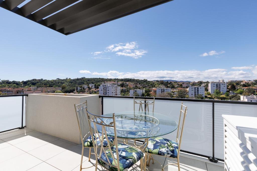 d'une table et de chaises en verre sur un balcon avec vue. dans l'établissement Immogroom - t2 new - bright - fully equipped, à Cannes