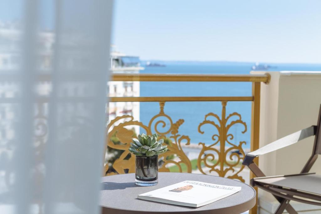 a table with a plant in a vase on a balcony at Electra Palace Thessaloniki in Thessaloniki