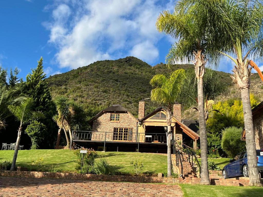 a house with palm trees in front of a mountain at Stonebreaker Country Lodge in Oudtshoorn