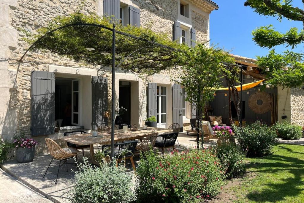 un patio avec une table et des chaises devant un bâtiment dans l'établissement Mas de village au calme, à Entraigues-sur-la-Sorgue