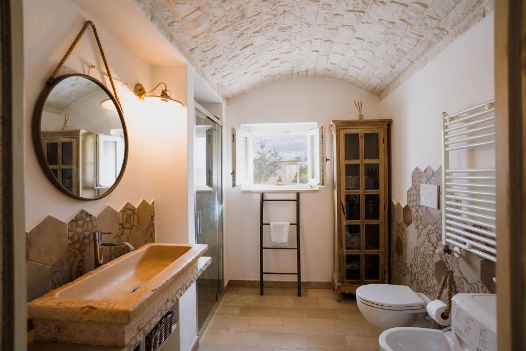une salle de bains avec un lavabo et un miroir dans l'établissement Trullo La Dama Forestiera, à Alberobello