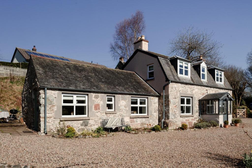 an old stone house sitting on a gravel driveway at Fernbank - Seasgair Lodges in Bridge of Cally